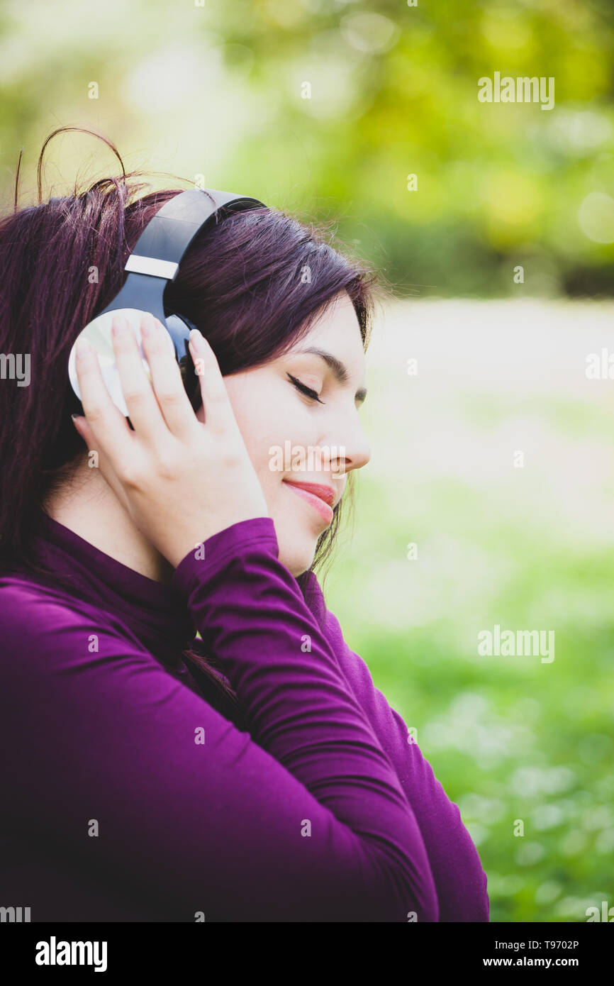 Schöne junge hübsche Frau im Park im freien Musik hören mit Kopfhörern. Stockfoto