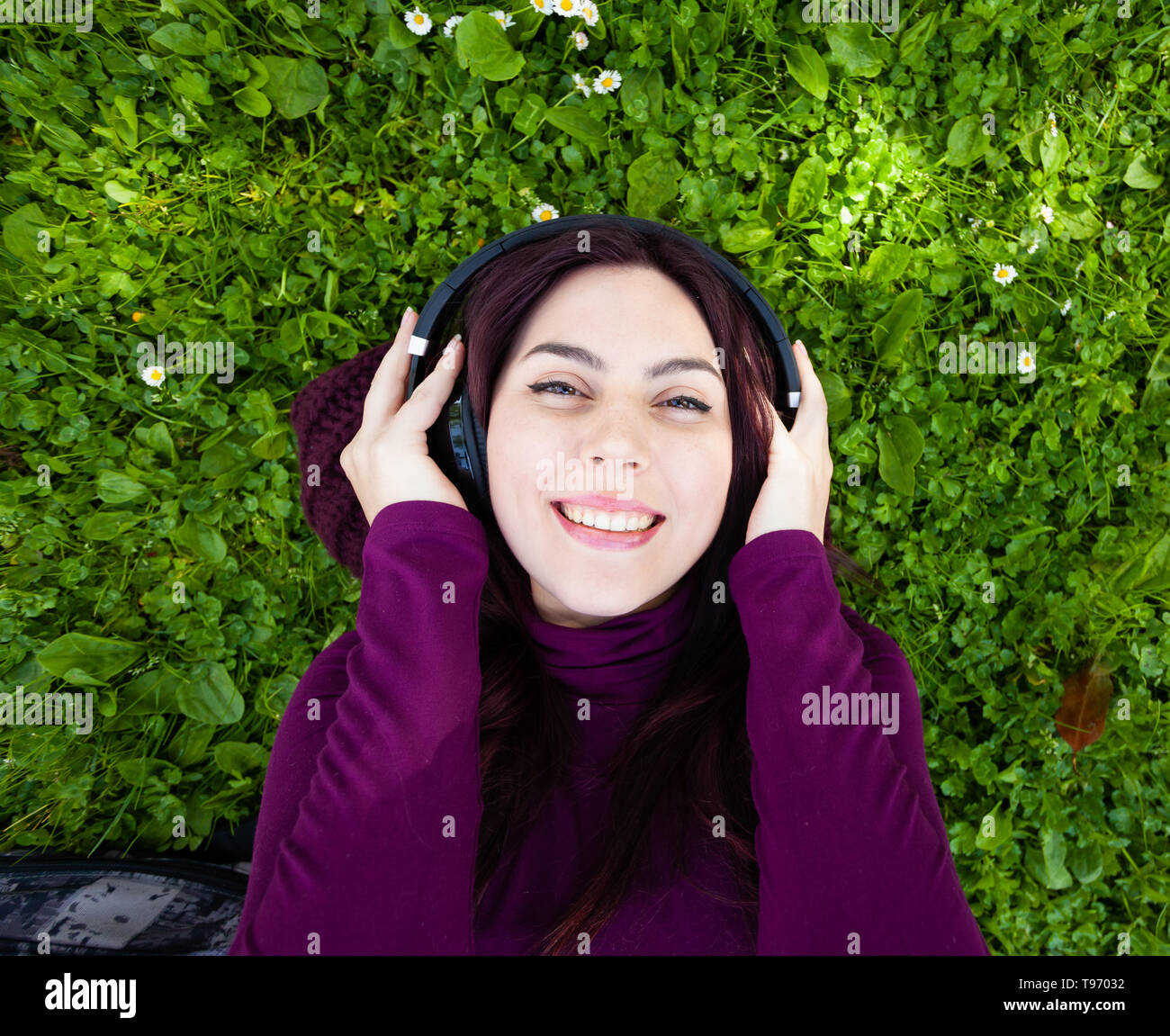Junge schöne Mädchen mit auf dem Rasen im Park Musik hören mit Kopfhörern. Ansicht von oben und Copyspace. Stockfoto