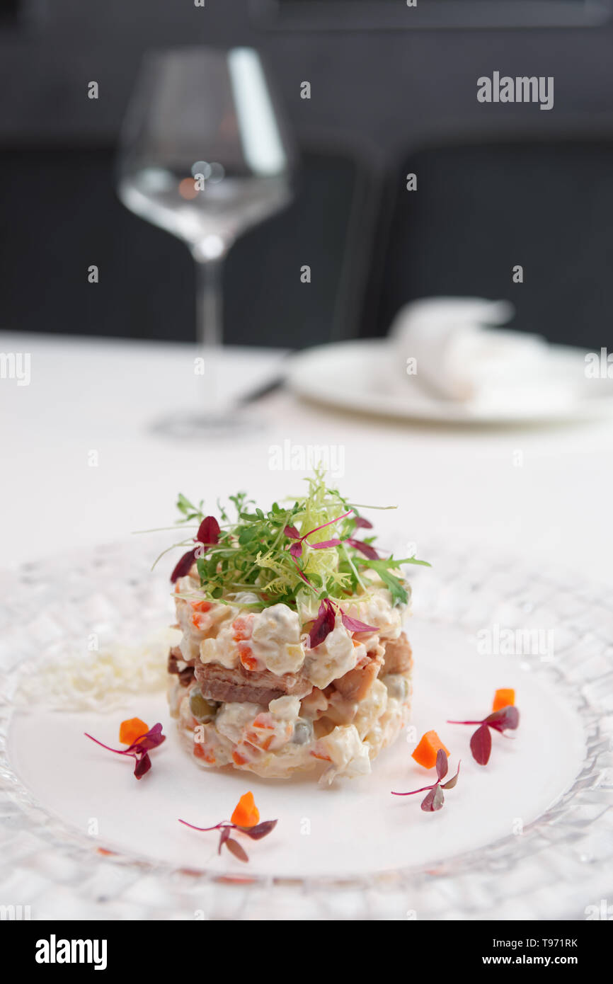 Russischer Salat in der modernen Weise gekocht serviert am Tisch im Restaurant Stockfoto