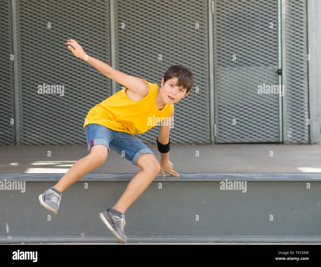 Vorderansicht eines lächelnden Jungen springen über eine metallische Zaun, während Sie die Kamera an einem hellen Tag Stockfoto