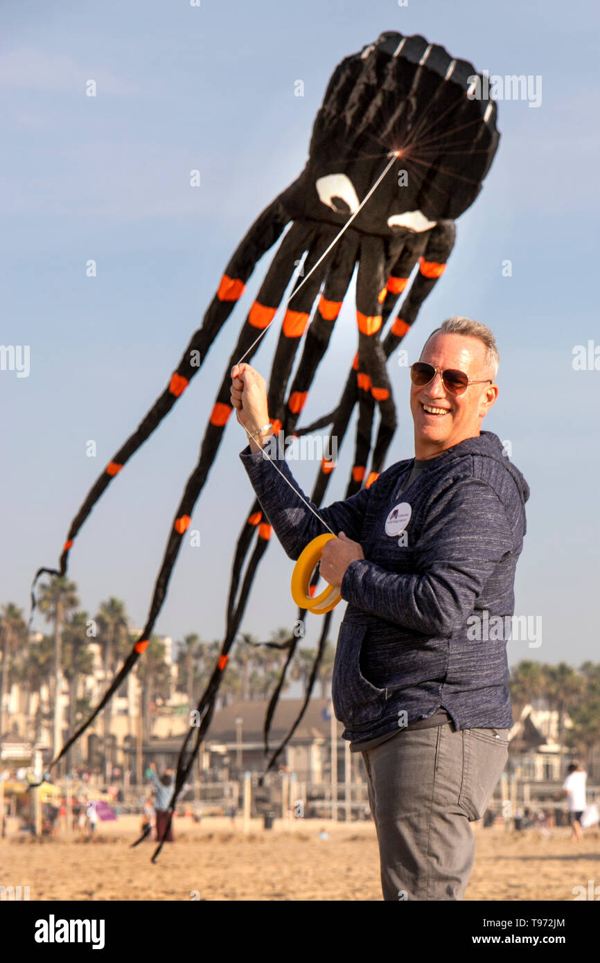 Eine lachende Mitglied einer Ozean Seite Drachenfliegen Festival Off zeigt seine Octopus - Bild Drachen in Huntington Beach, CA. Stockfoto