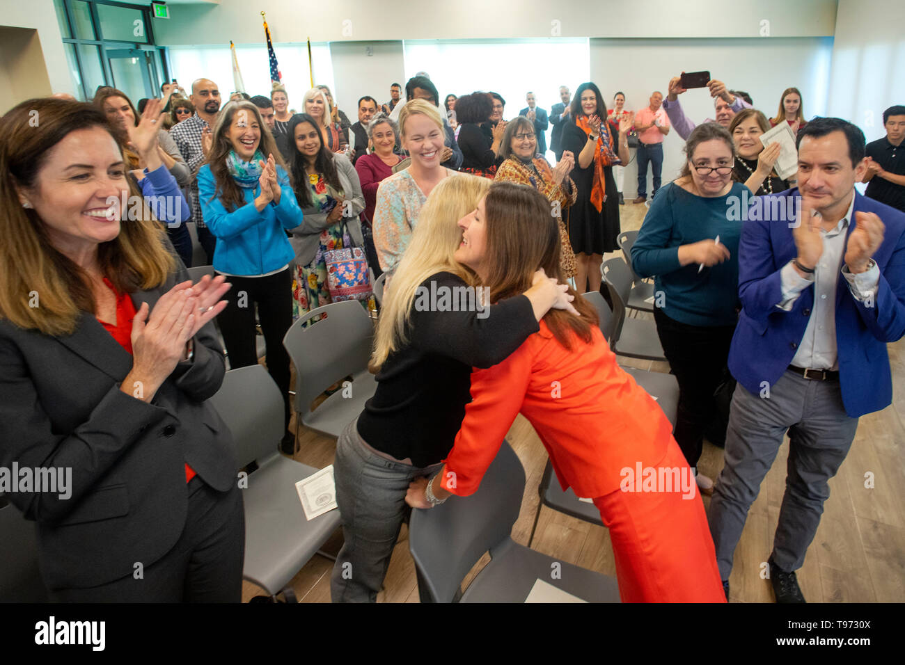 Eine Frau Politiker wird begrüsst mit Umarmungen und Applaus bei ihrer Vereidigung-in für ein öffentliches Amt in Newport Beach, CA. Stockfoto