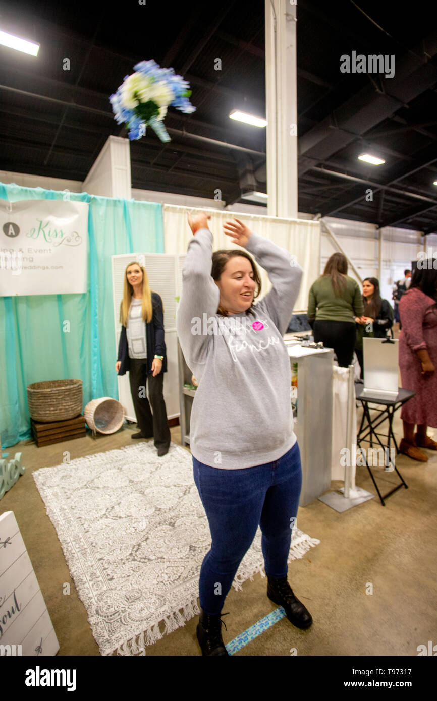 Eine engagierte junge Frau wirft den Brautstrauß am Korb im Hintergrund zielen für einen Lottoschein zu einem bridal Fair in Costa Mesa, CA zu qualifizieren. Stockfoto