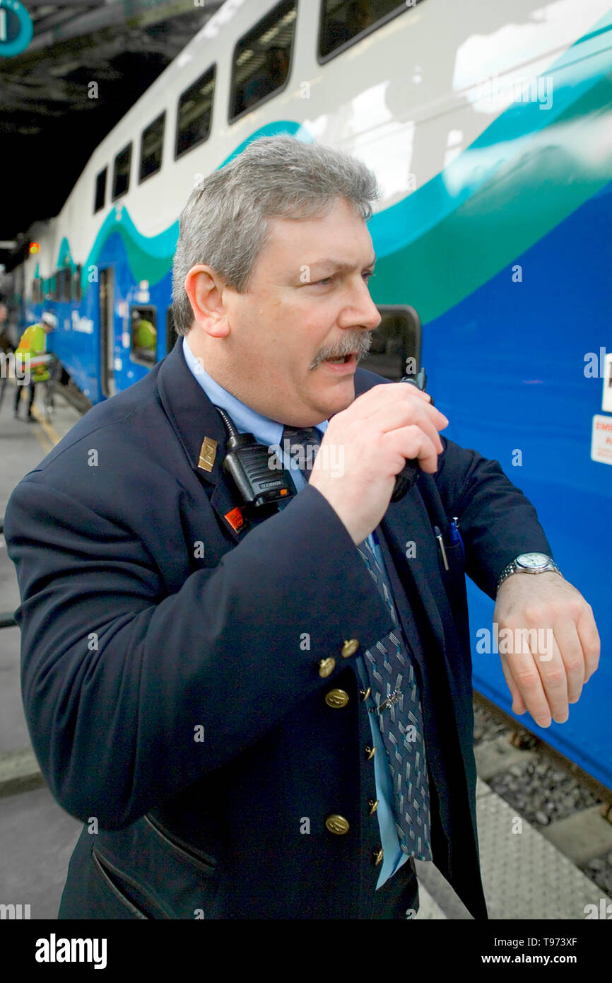 Ein Personenzug Dirigent prüft seine Uhr vor Bekanntgabe der Zeit Abfahrt eines Zuges aus Seattle, WA. Stockfoto