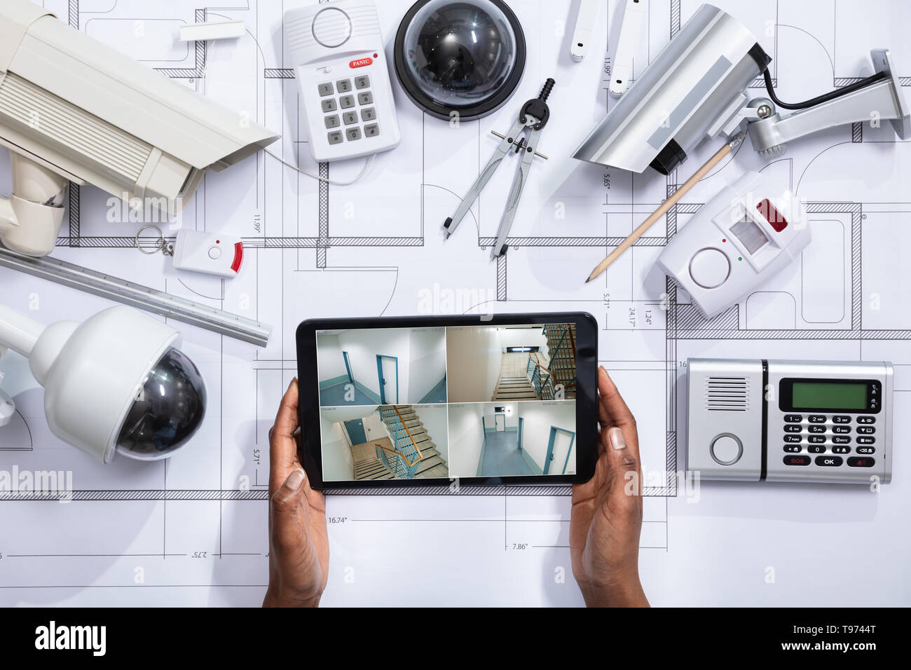 Einen erhöhten Blick auf die Person, die die Aufnahmen auf Digital Tablet mit Ausrüstungsgegenstände für die Gefahrenabwehr auf dem Bauplan Stockfoto