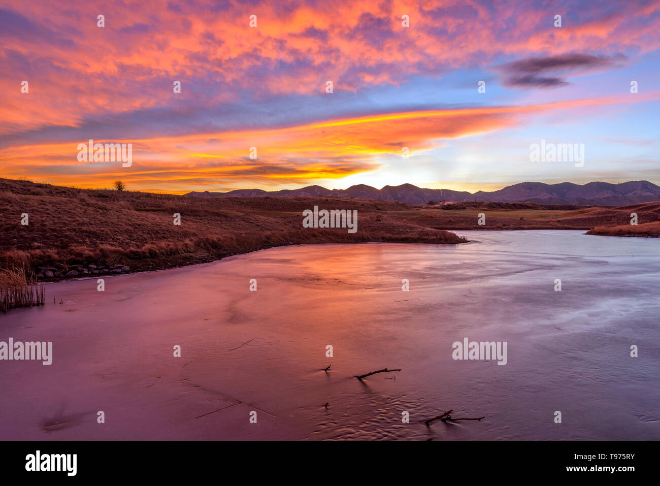 Sonnenuntergang Winter Lake - eine bunte winter Sonnenuntergang an einem zugefrorenen Bergsee. Bear Creek Park, Denver-Lakewood, Colorado, USA. Stockfoto