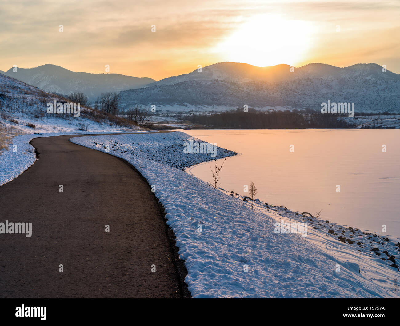 Sunset Trail - ein Winter Sonnenuntergang Blick auf einen gepflasterten Wander-/Radweg entlang eines gefrorenen Bergsee. Colorado, USA. Stockfoto