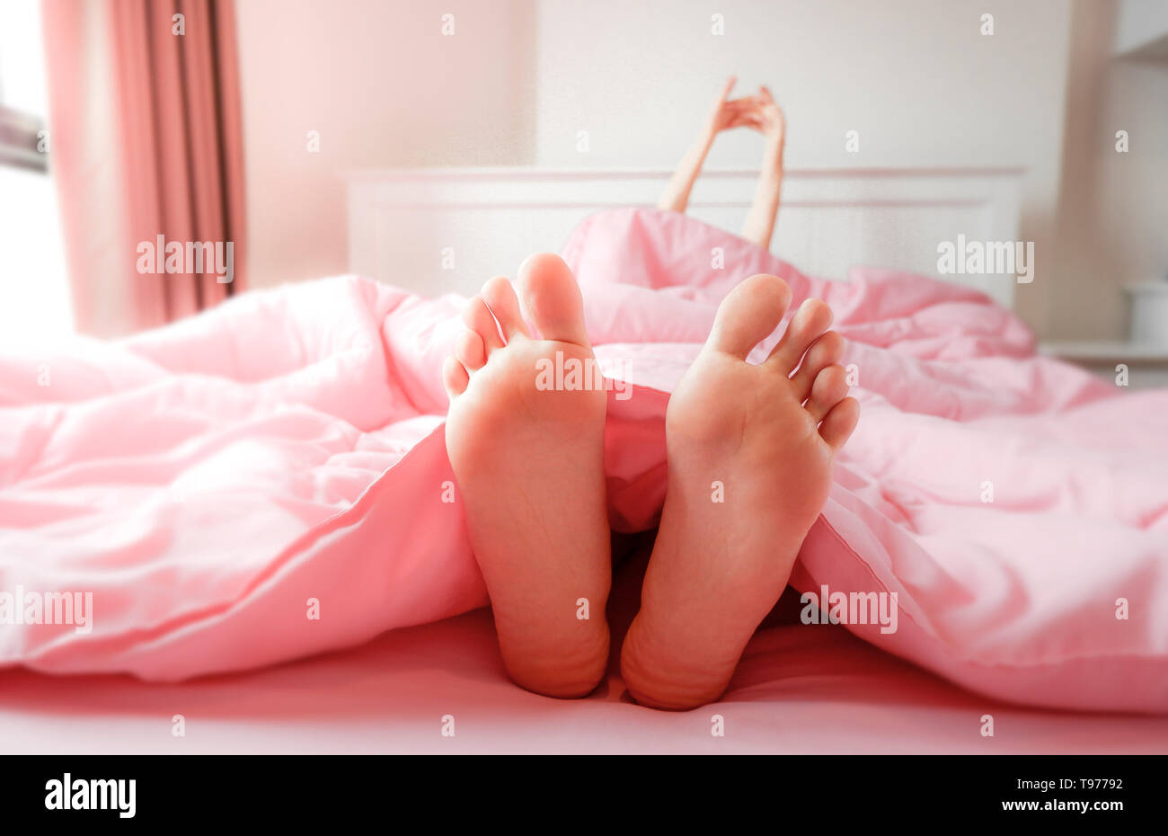 Fuß in Bett zu Hause, Schlafen & Entspannen. Zwei Füße auf dem Bett in rosa  Bettwäsche. Schöne junge Frau Barfuß im Schlafzimmer Hintergrund. Weibliche  Füße Stockfotografie - Alamy