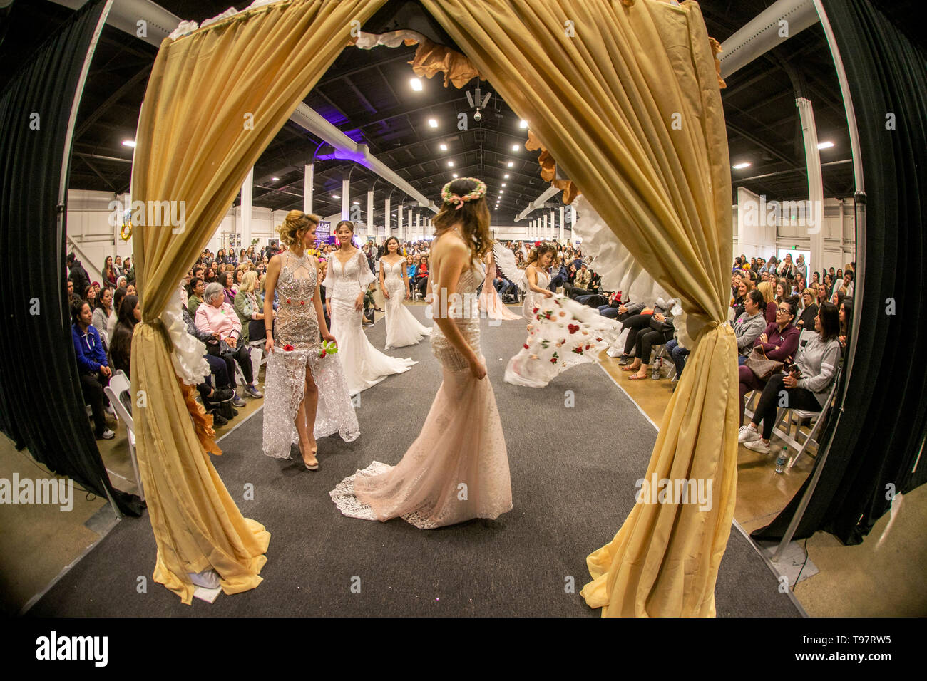 Hochzeit Kleider werden durch eine multiethnische Gruppe von Frauen modelliert -- eine getragen Angel Wings - an einer bridal Expo in Costa Mesa, CA. Stockfoto
