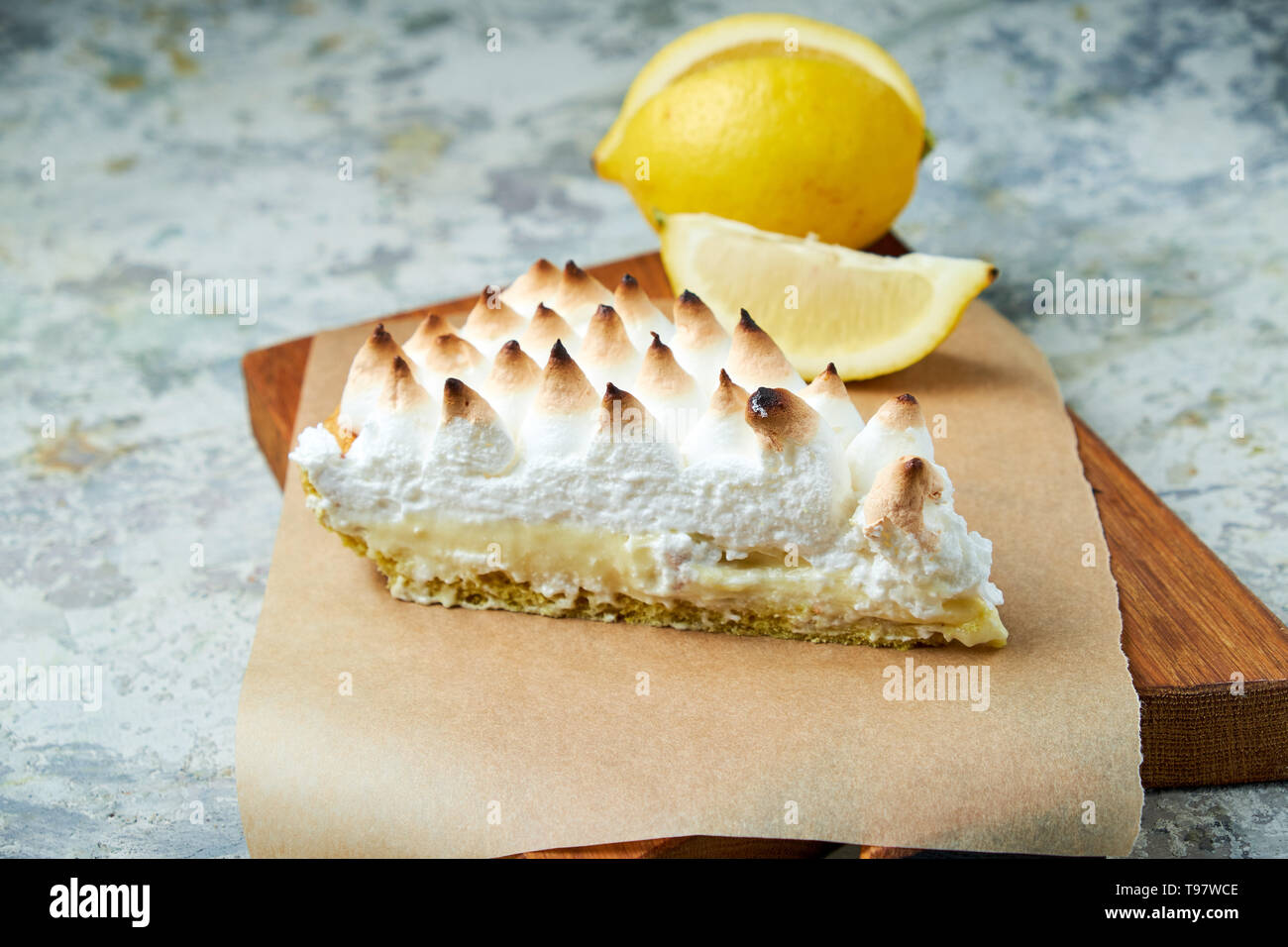 Ein Stück Zitrone Törtchen mit einer Scheibe Zitrone auf einem holzbrett eingerichtet. Grau strukturierten Hintergrund. Schöne Gerichte. Nachtisch. Lebensmittelkette Stockfoto