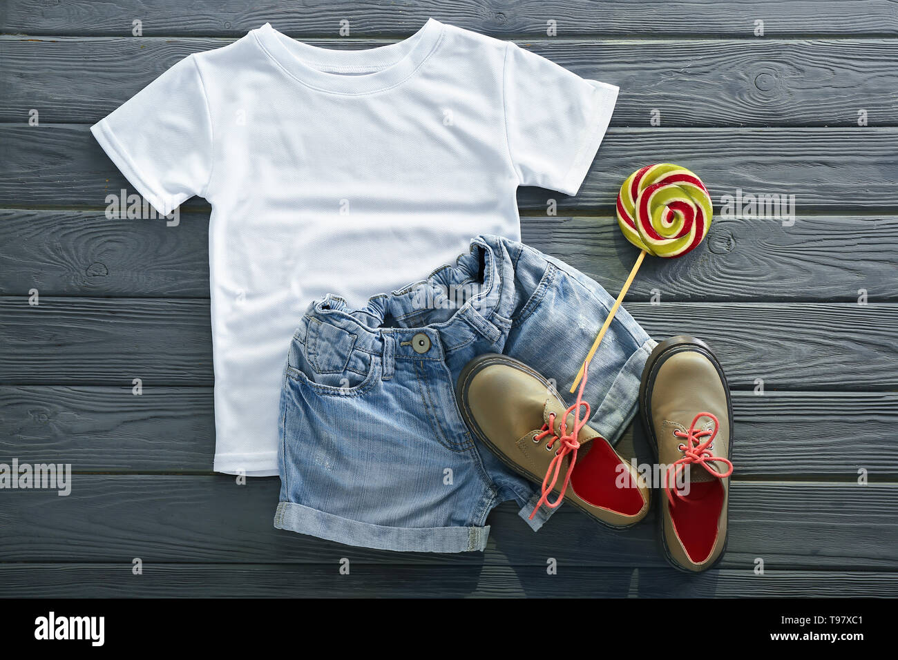 Stylisches Outfit mit Schuhen und Lollipop auf hölzernen Hintergrund Stockfoto