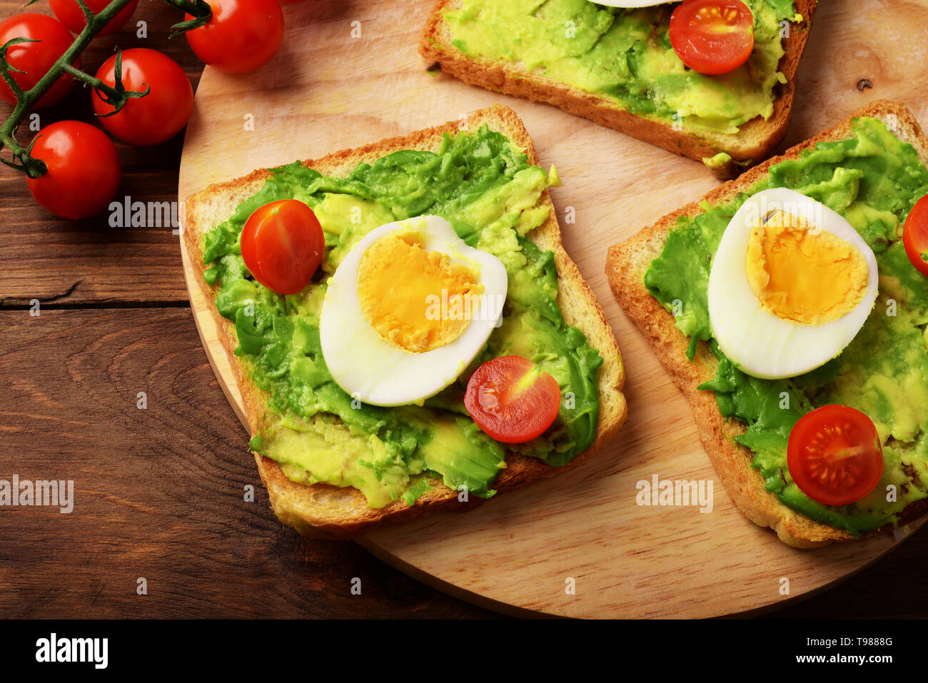 Toast mit Avocado, Tomaten und Eier сherry auf rustikalen hölzernen Hintergrund Stockfoto