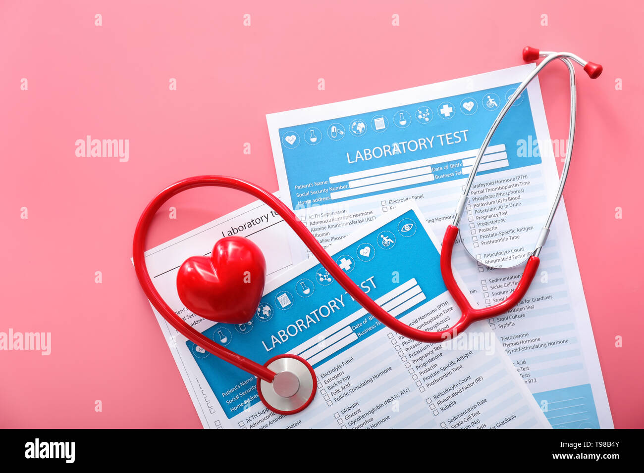 Stethoskop mit roten Herzen und Listen von Labortests auf farbigen Hintergrund. Gesundheit Konzept Stockfoto