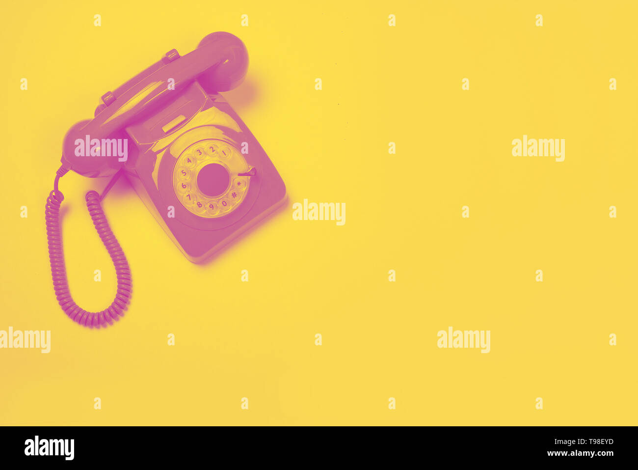 Rosa Retro Telefon auf gelbem Hintergrund in einem Duo Tone Design mit Platz für Kopie Stockfoto
