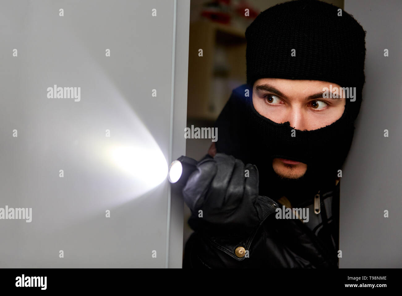 Einbrecher im Haus mit Taschenlampe sucht nach Beute in einem Einbruch Stockfoto