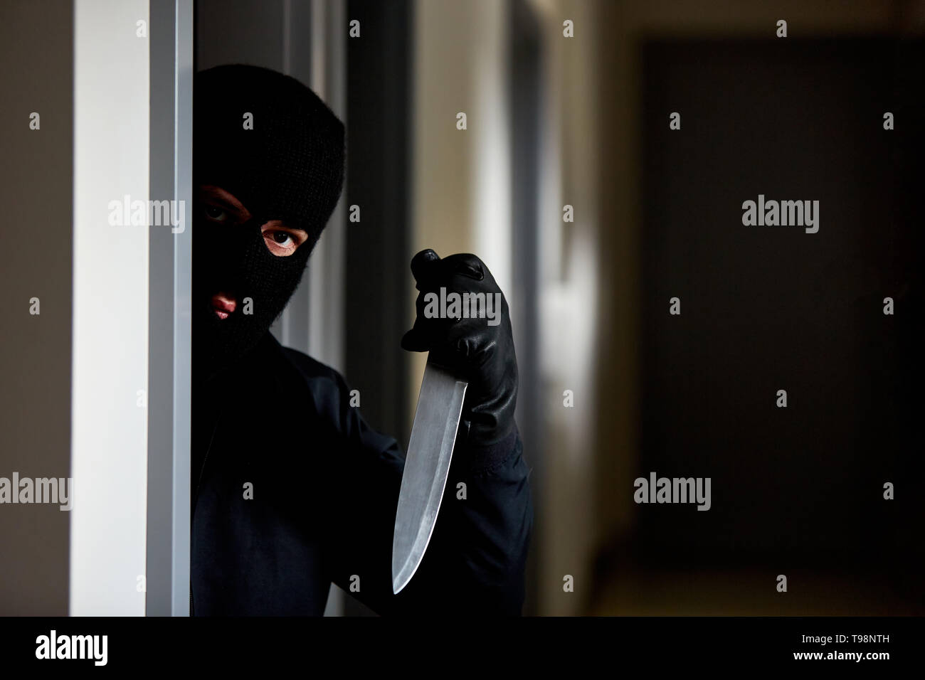 Maskierte Räuber mit Messer als Waffe im Haus wartet Stockfoto