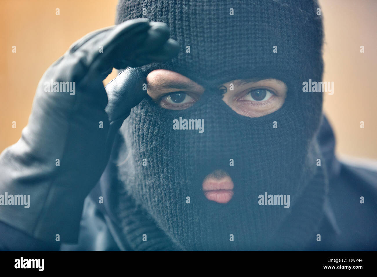 Polizei SEK Einsatzkraft mit Sturm Maske wirkt durch ein Fenster in ein Haus Stockfoto