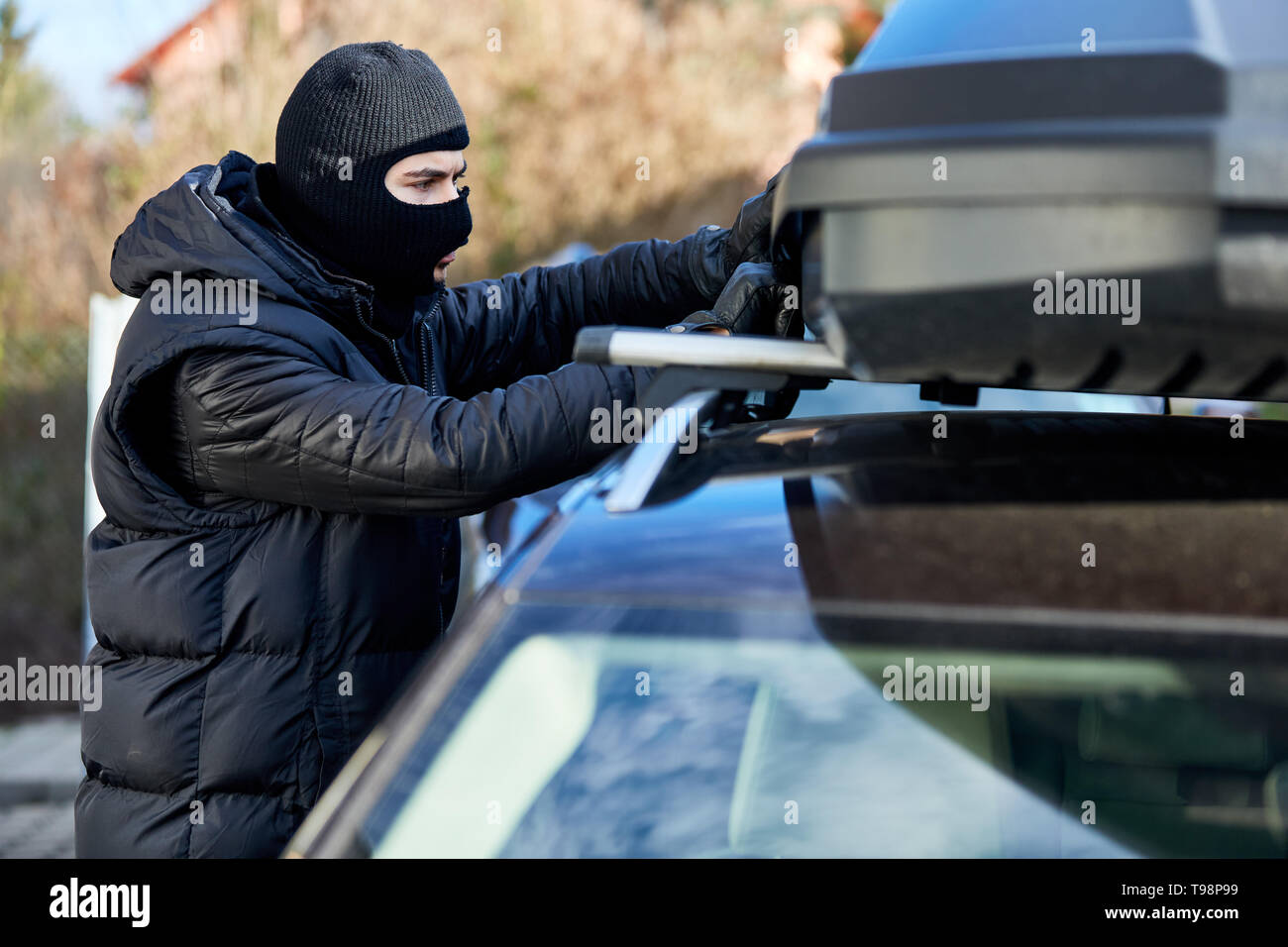 Dieb öffnet Dachbox oder Dachgepäckträger auf ein Auto für Diebstahl Stockfoto