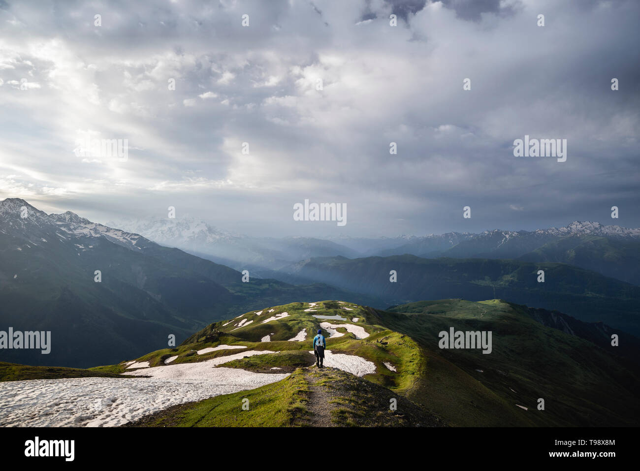 Wanderer vor der Schneefelder den Blick über die Berge und Täler der Großen Kaukasus im Streiflicht, Oberswanetien, Georgien Stockfoto