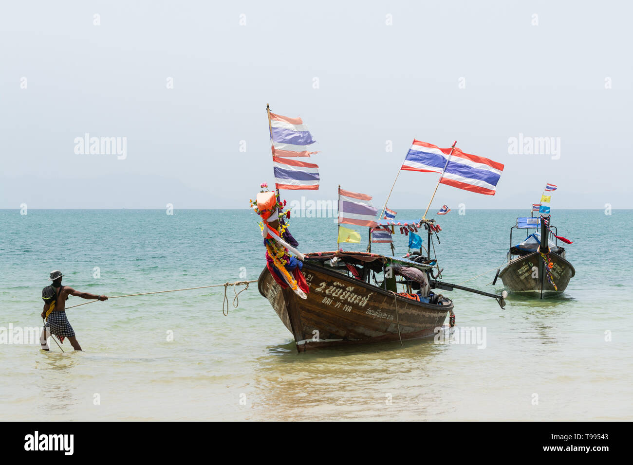 Krabi, Thailand - März 2019: long tail Boote aus Holz mit Thai flags an Railay Strand vertäut. Stockfoto