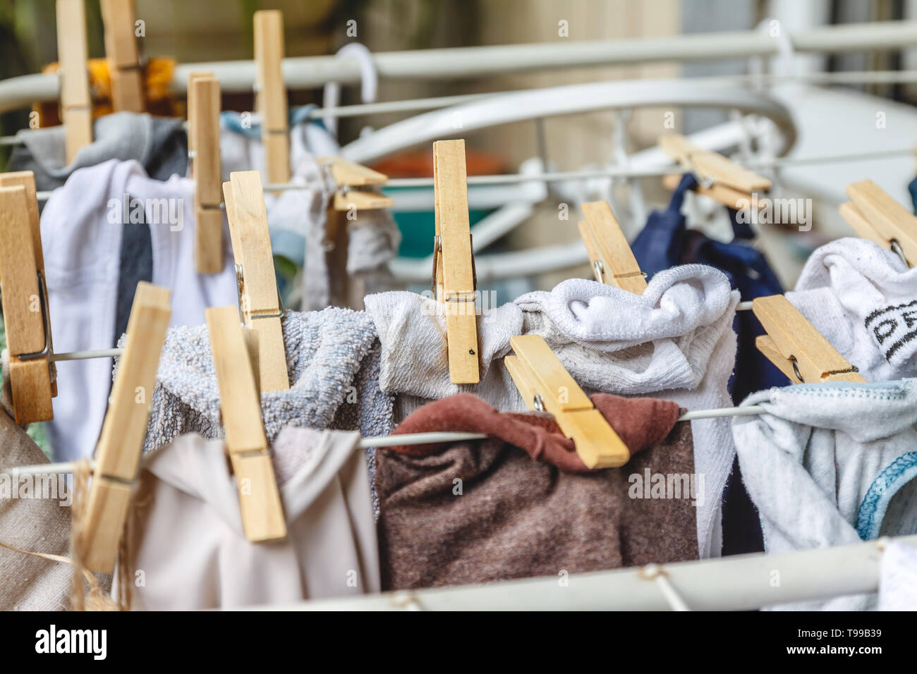 Weiße und farbige Bettwäsche auf die Wäscheleine mit Wäscheklammern aus Holz zu trocknen. Stockfoto