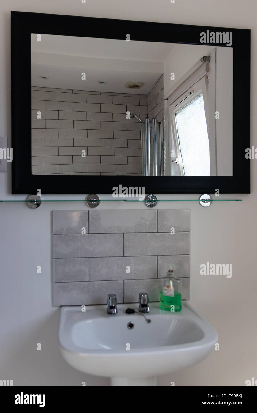 Ein gefliestes Bad Waschbecken mit Spiegel über Stockfoto