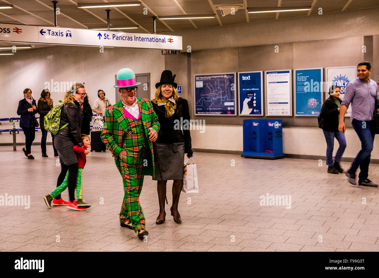 Paar gekleidet in extravaganter Kleidung, wandern durch die U-Bahnstation Kings Cross, London, England, Großbritannien Stockfoto