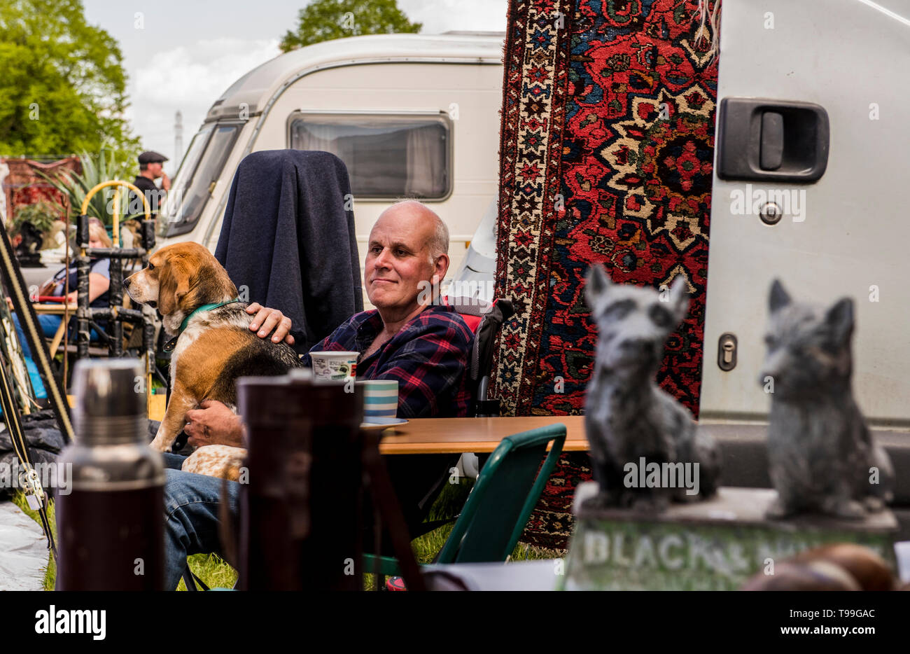 Mann sitzt vor dem Wohnmobil an Antiquitäten Stall, Streichelzoo Hund auf seinem Schoß, Ripley, North Yorkshire, England, Großbritannien Stockfoto