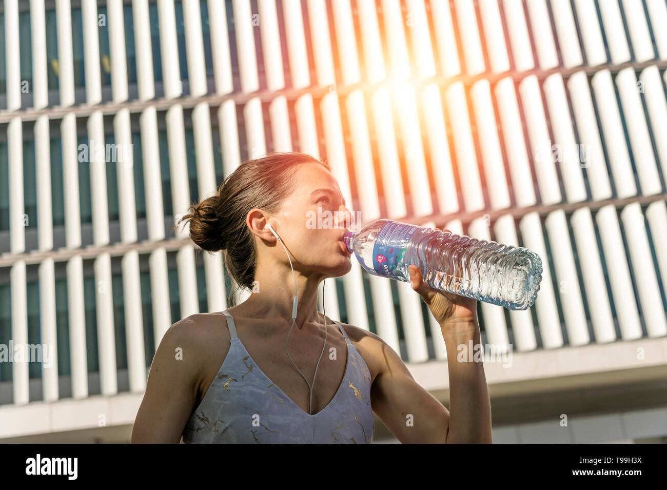 Sportliche Frau trinkt Wasser aus einer Flasche, rehydrieren nach Übung. Stockfoto