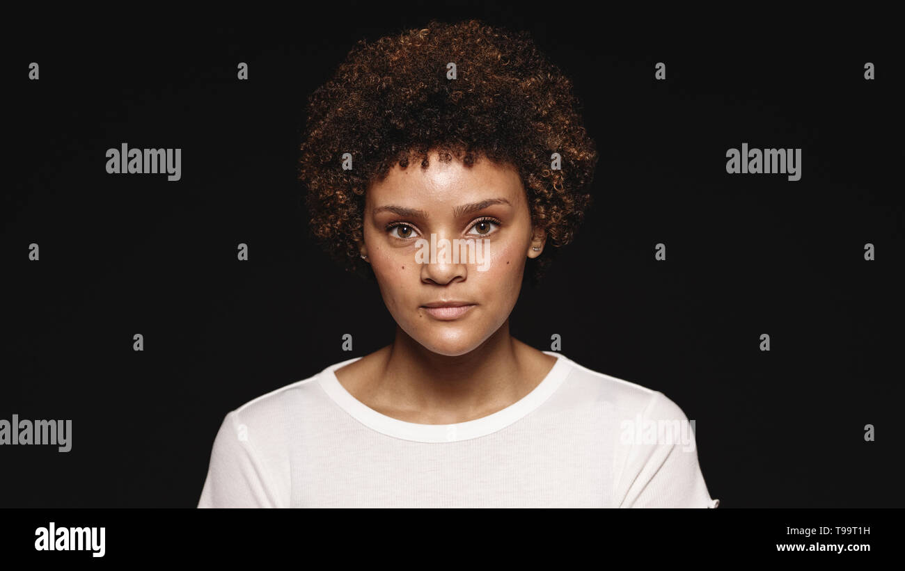 Porträt einer jungen Frau auf schwarzem Hintergrund isoliert. Frau mit lockigem Haar auf Kamera. Stockfoto