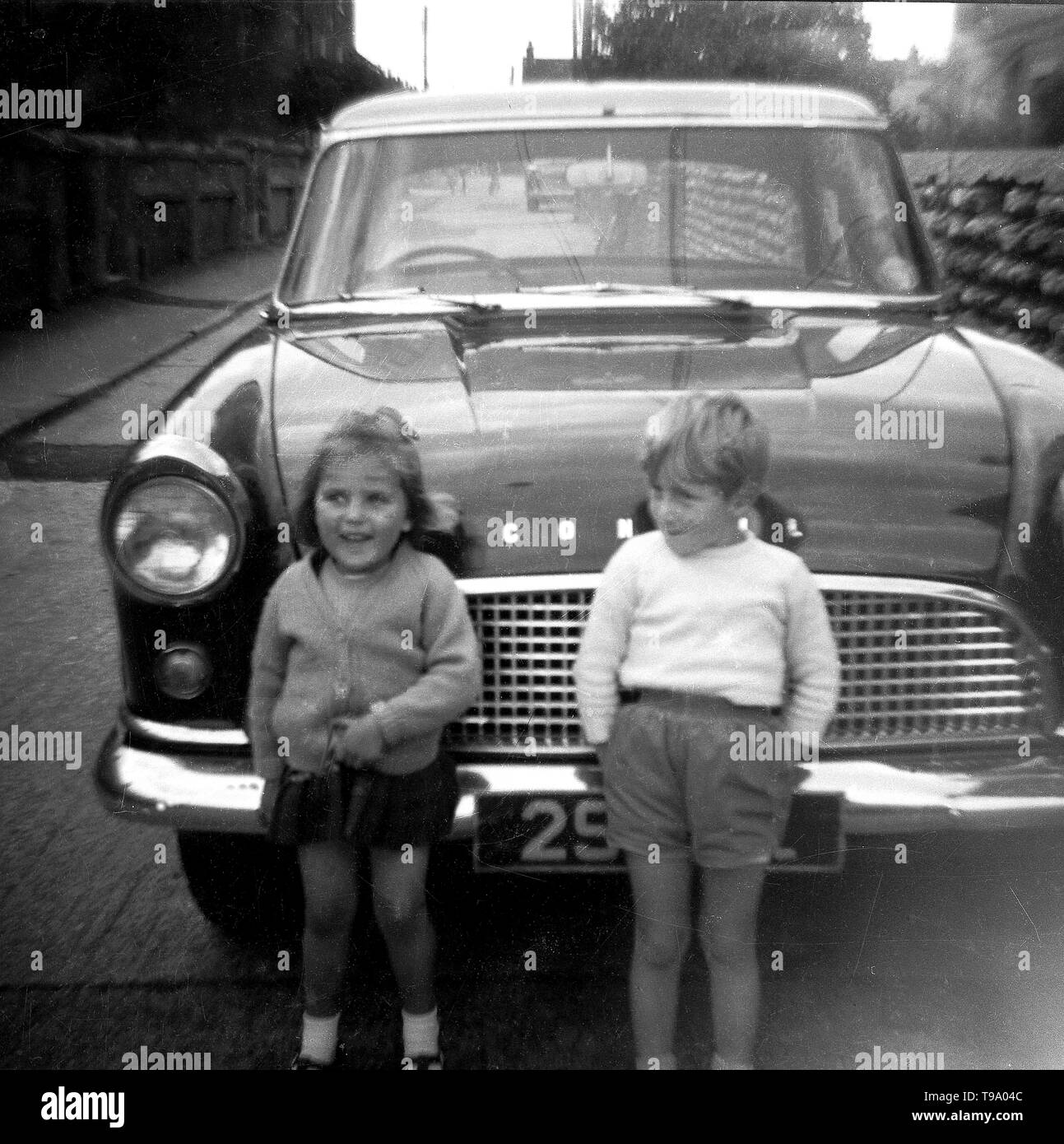 Zwei glücklich aussehende junge Kinder vor ein Ford Consul Motor Car c 1960 darstellen. Foto von Tony Henshaw Stockfoto