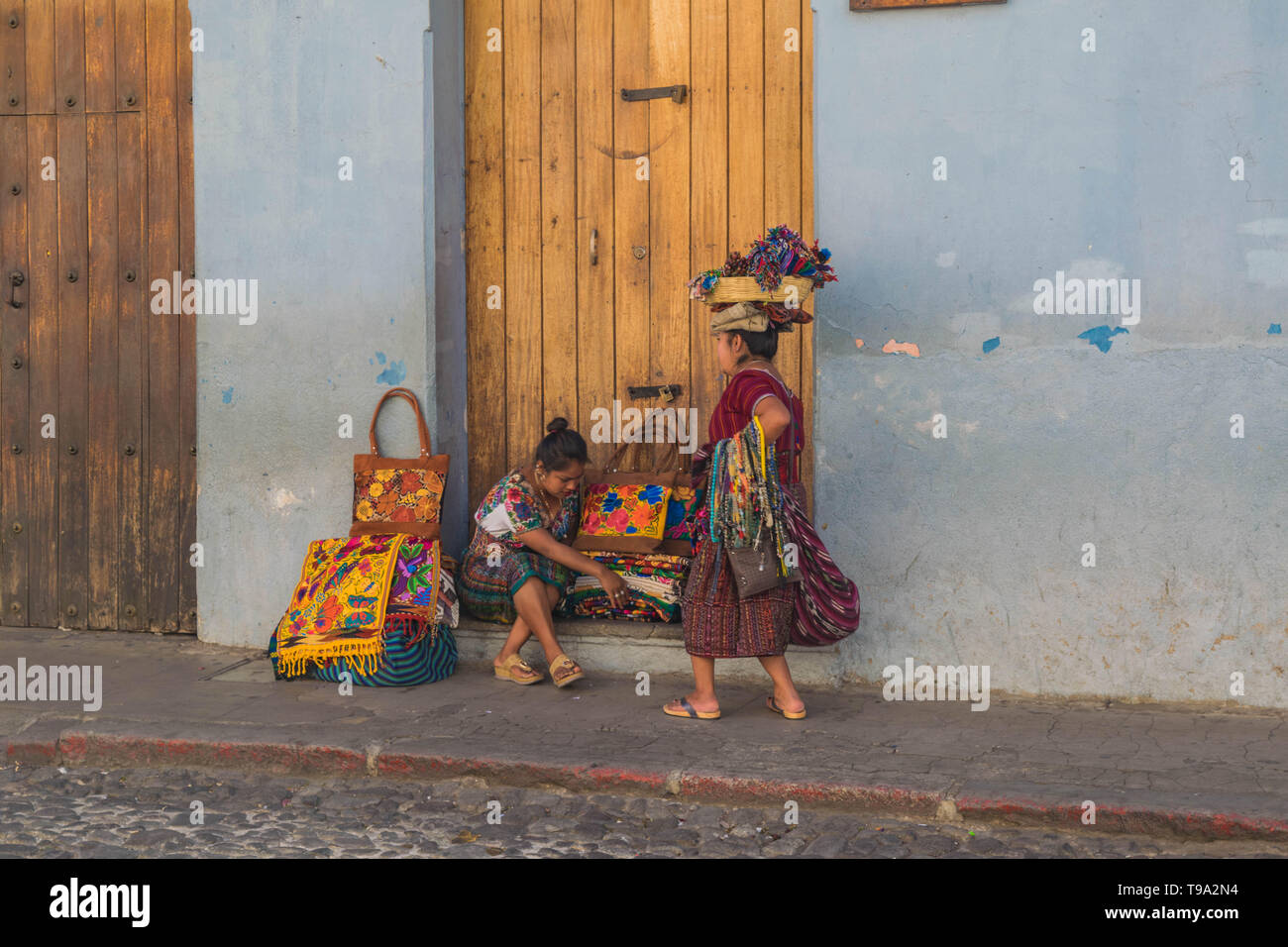 Zwei Frauen Straßenhändler in traditioneller Kleidung, eine mit einem Korb auf dem Kopf, Verkauf von guatemaltekischen Güter auf einer Straße mit Kopfsteinpflaster in Antigua Guatemala Stockfoto Zwei Frauen Straßenhändler in traditioneller Kleidung, eine mit einem Korb auf dem Kopf, Verkauf von guatemaltekischen Güter auf einer Straße mit Kopfsteinpflaster in Antigua Guatemala Stockfoto