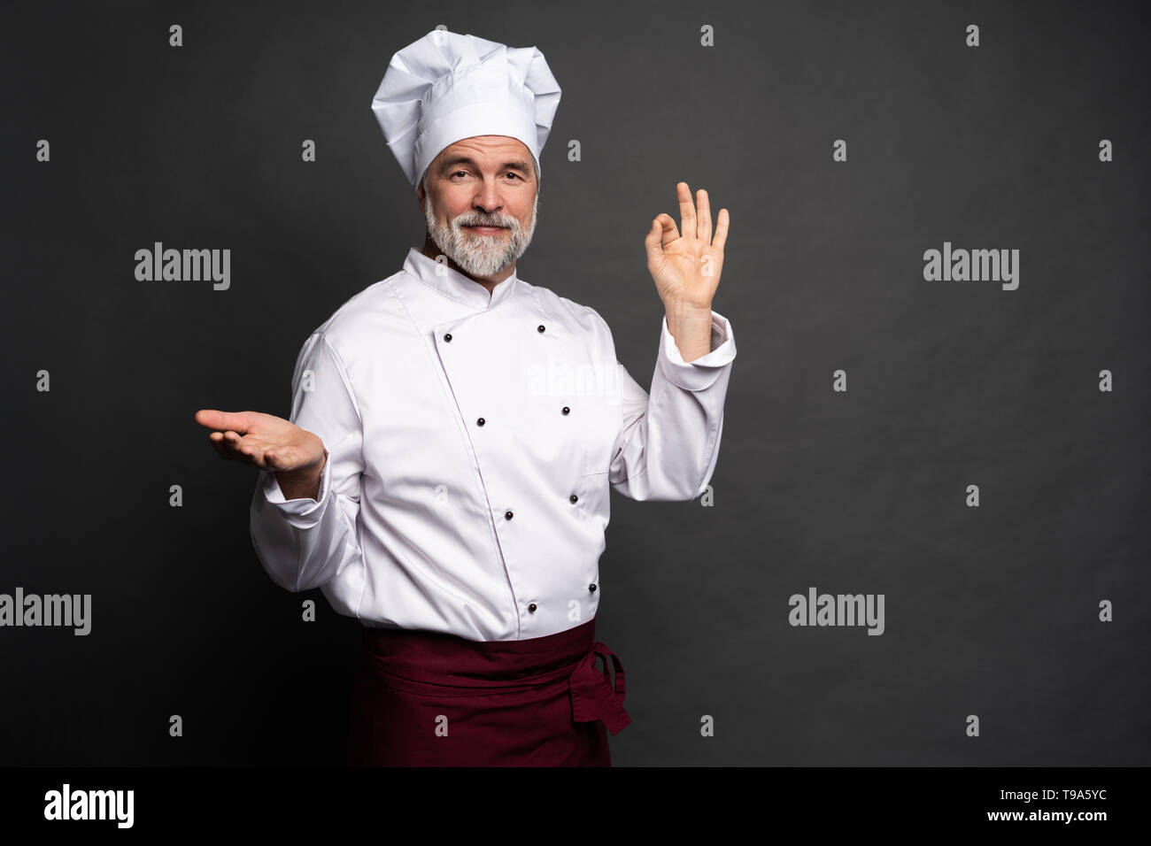 Koch, lecker lecker Geste durch Küssen Finger. Zuversichtlich bärtigen Mann Koch in weiße Uniform mit perfekter unterzeichnen. Stockfoto
