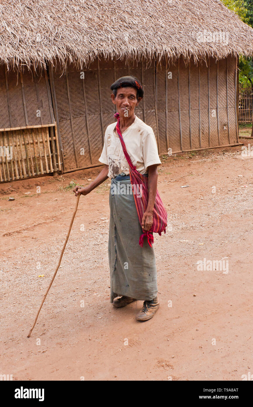 Ein Mann der Shan-Leute, der einen Stock hält, eine Zigarre raucht, den traditionellen birmanischen Rock trägt, longyi, und eine traditionelle Schultertasche, Myanmar Stockfoto