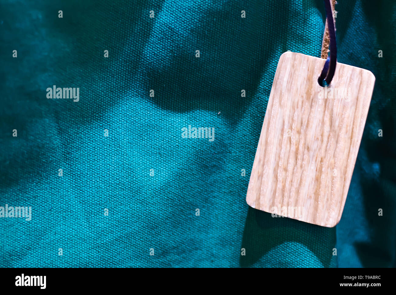 Holz- tag mit dünnen Lederband blau grün canvas Nahaufnahme Textur Hintergrund Stockfoto