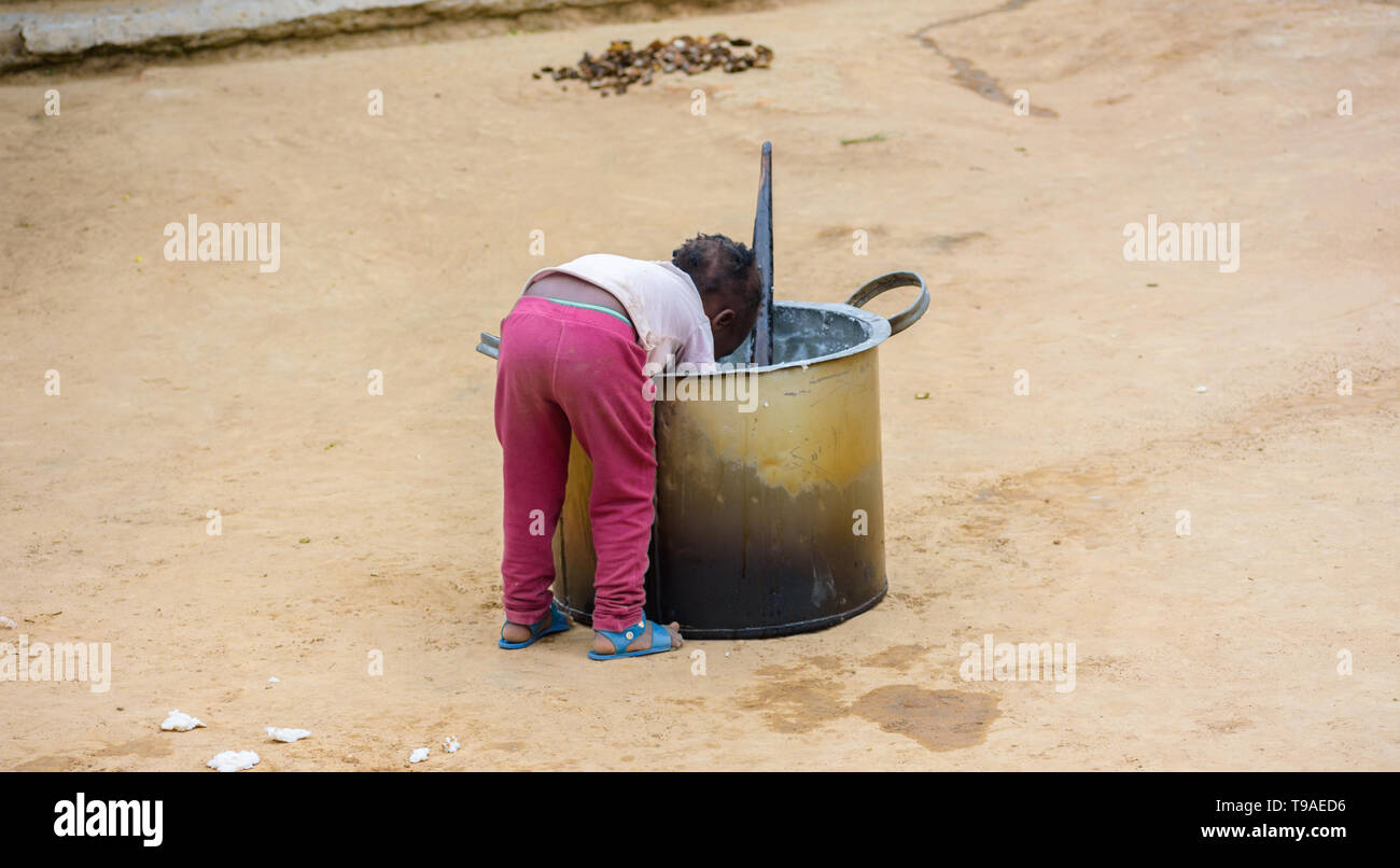 Eine malawische Kind lehnt sich über einem großen Kochtopf nsima oder Haferbrei zu kratzen Stockfoto