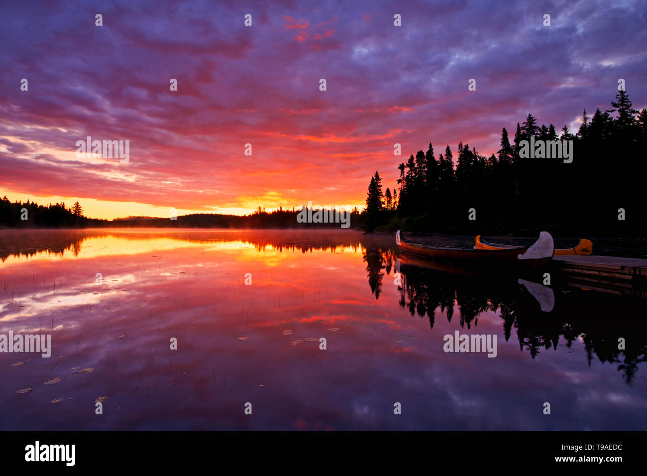 Reflexion von Wolken in Lac du Fou bei Sonnenaufgang mit Kanus La Mauricie Nationalpark Quebec Kanada Stockfoto