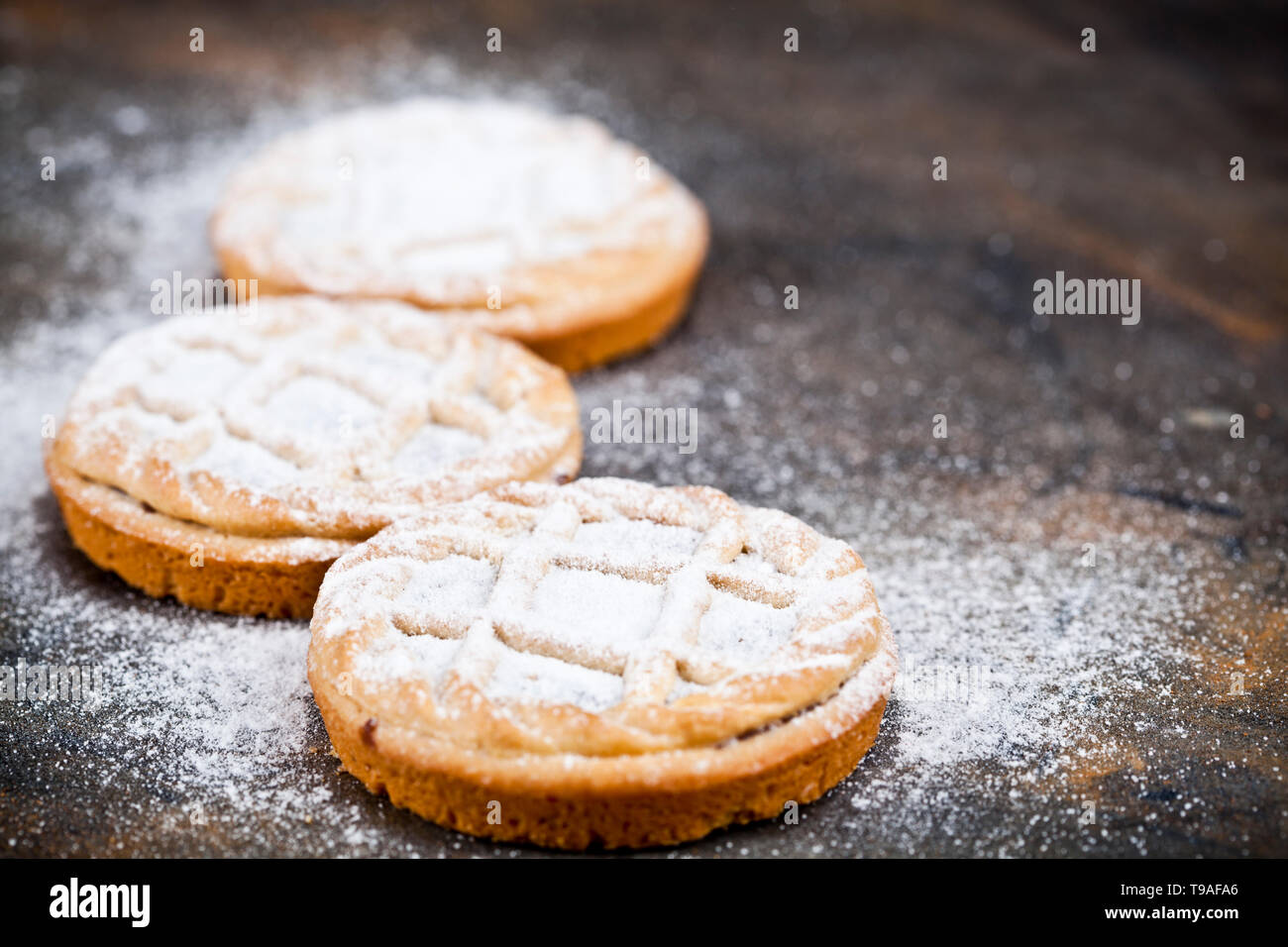 Frisch gebackene Torten mit Schokolade und Zucker füllen Pulver auf schwarzem Hintergrund. Süße Speisen Konzept mit kopieren. Stockfoto