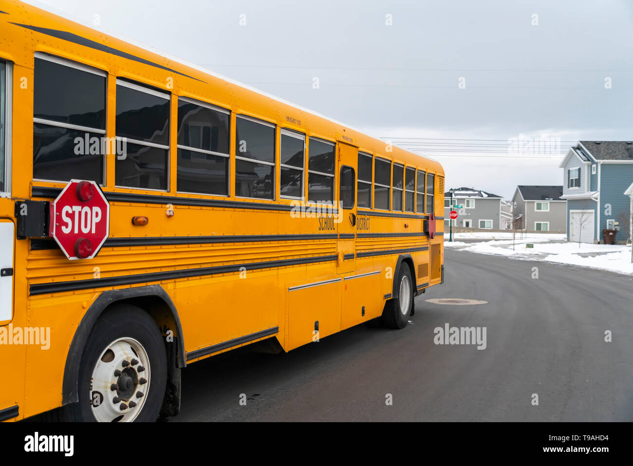 Seitenansicht eines School Bus auf einer Straße, die durch verschneite Häuser im Winter Stockfoto