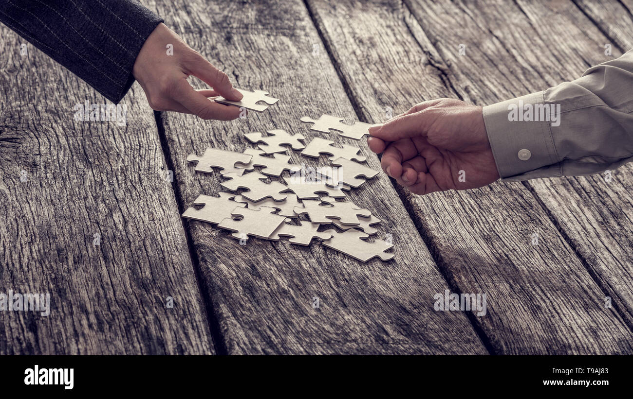 Zwei verschiedene Hände nicht identifizierbare Geschäftsleute erreichen für Puzzleteile vom Stapel. Stockfoto