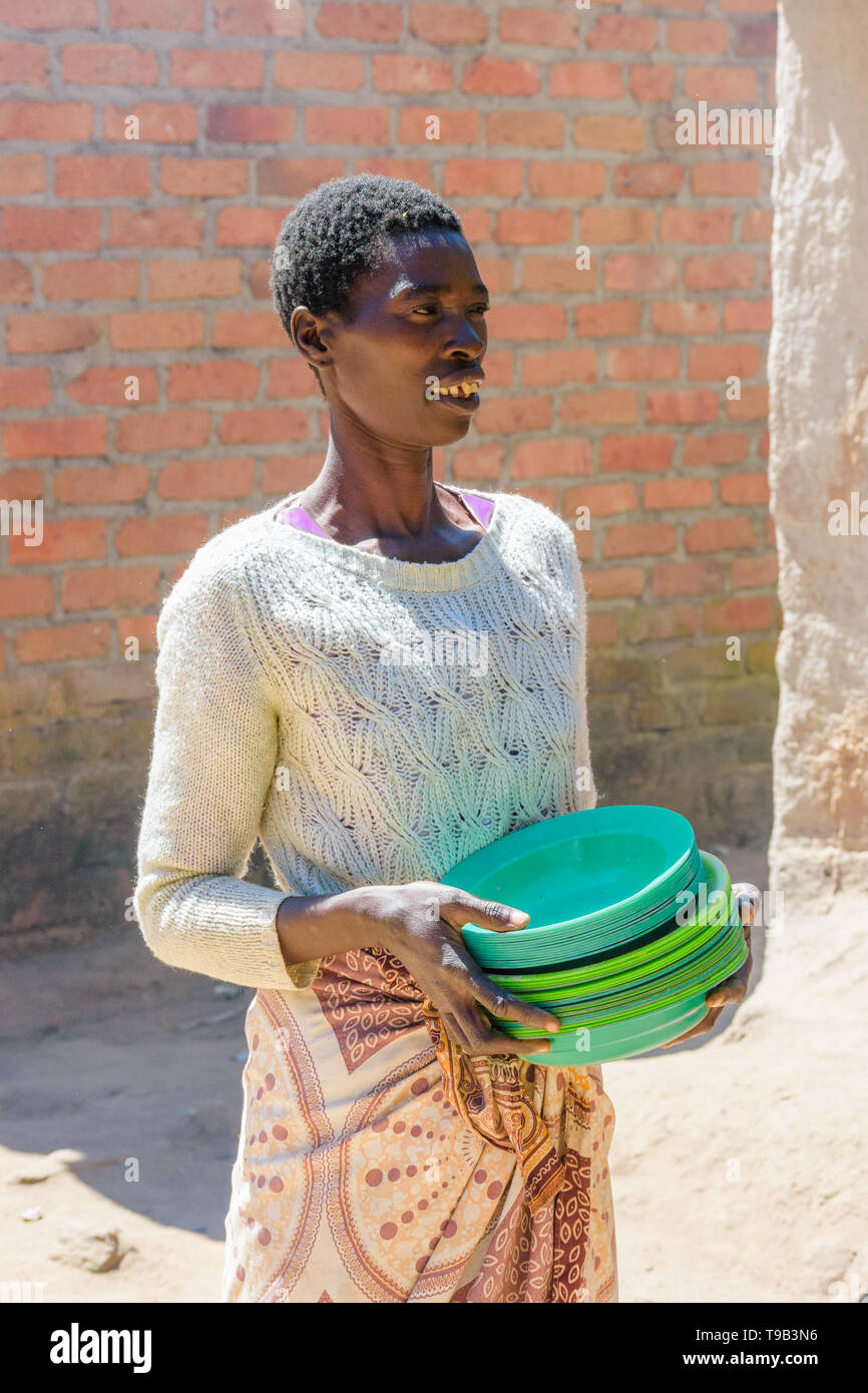 Malawische Frau mit mehreren Schalen aus Kunststoff Stockfoto