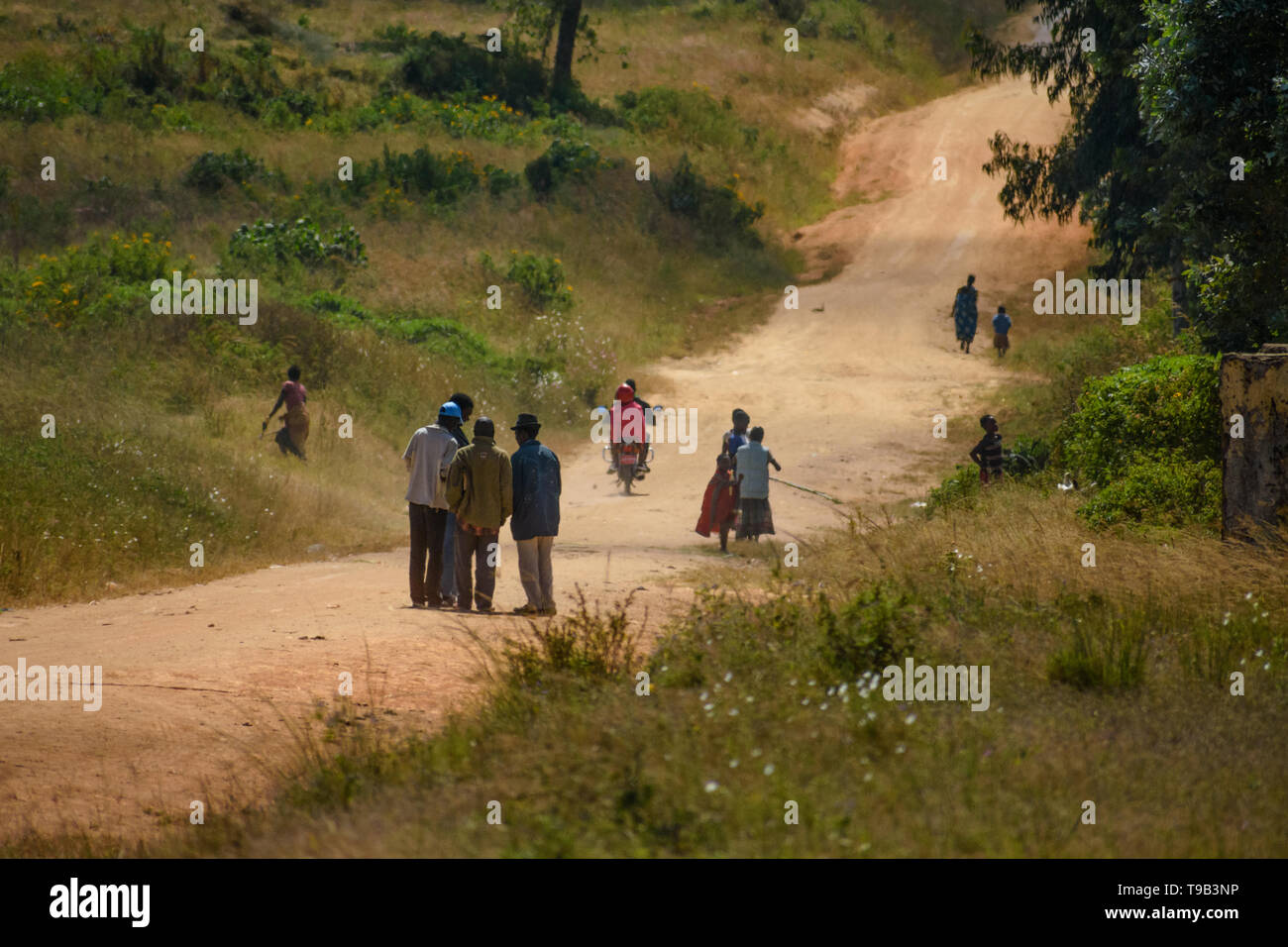 Malawier zu Fuß auf und lebt eine unbefestigte Straße, die wie ein Magnet für Menschen in einer Malawischen Dorf Rechtsakte Stockfoto