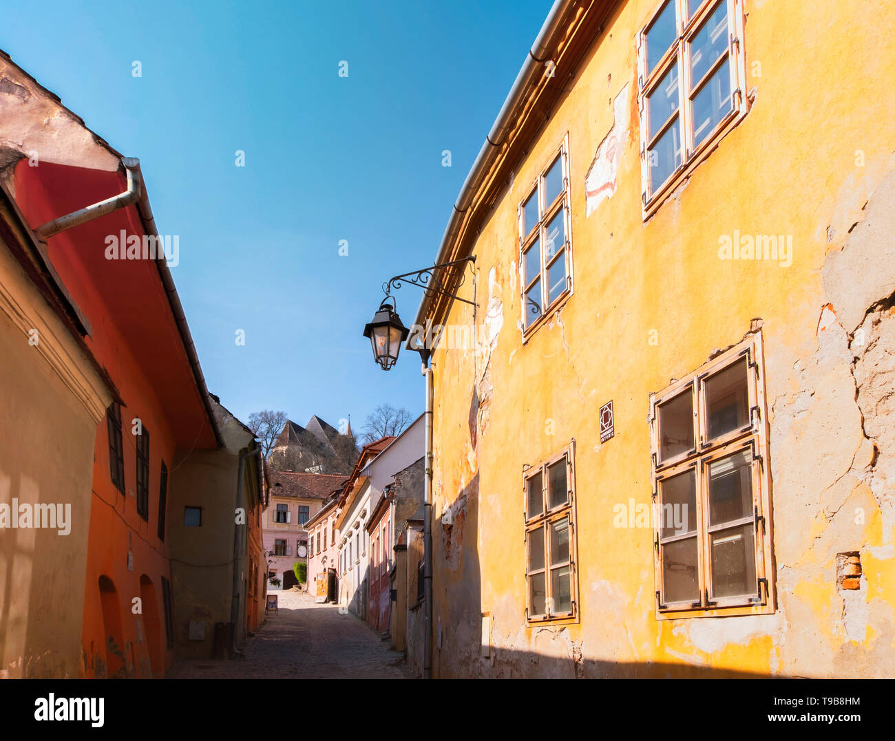 Alten bunten Häuser in Sighisoara Zitadelle auf einem sonnigen Frühling morgens mit einem Blick auf die Kirche auf dem Hügel. Stockfoto