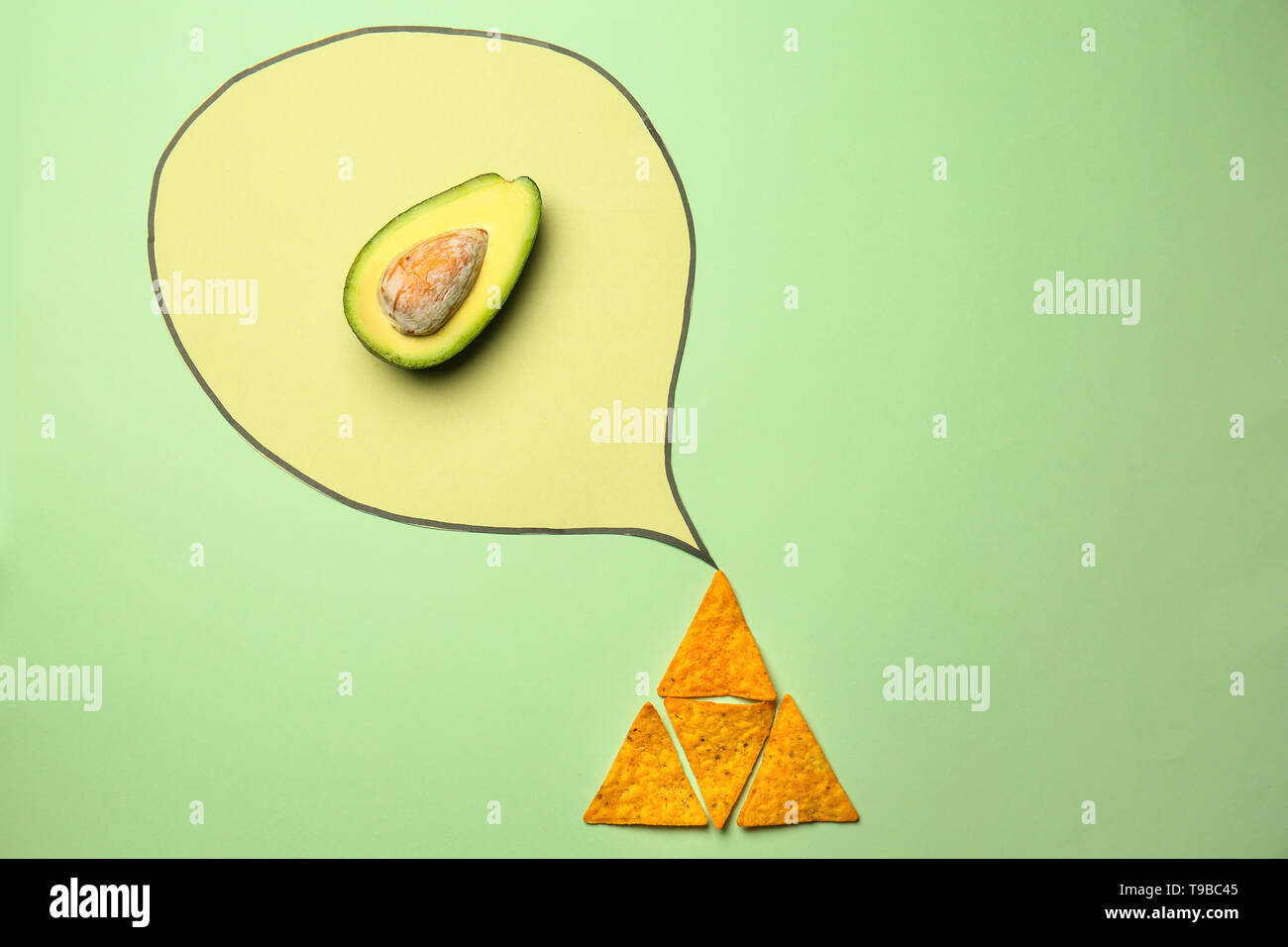 Kreative Komposition mit Mais Chips und Avocado auf farbigen Hintergrund Stockfoto
