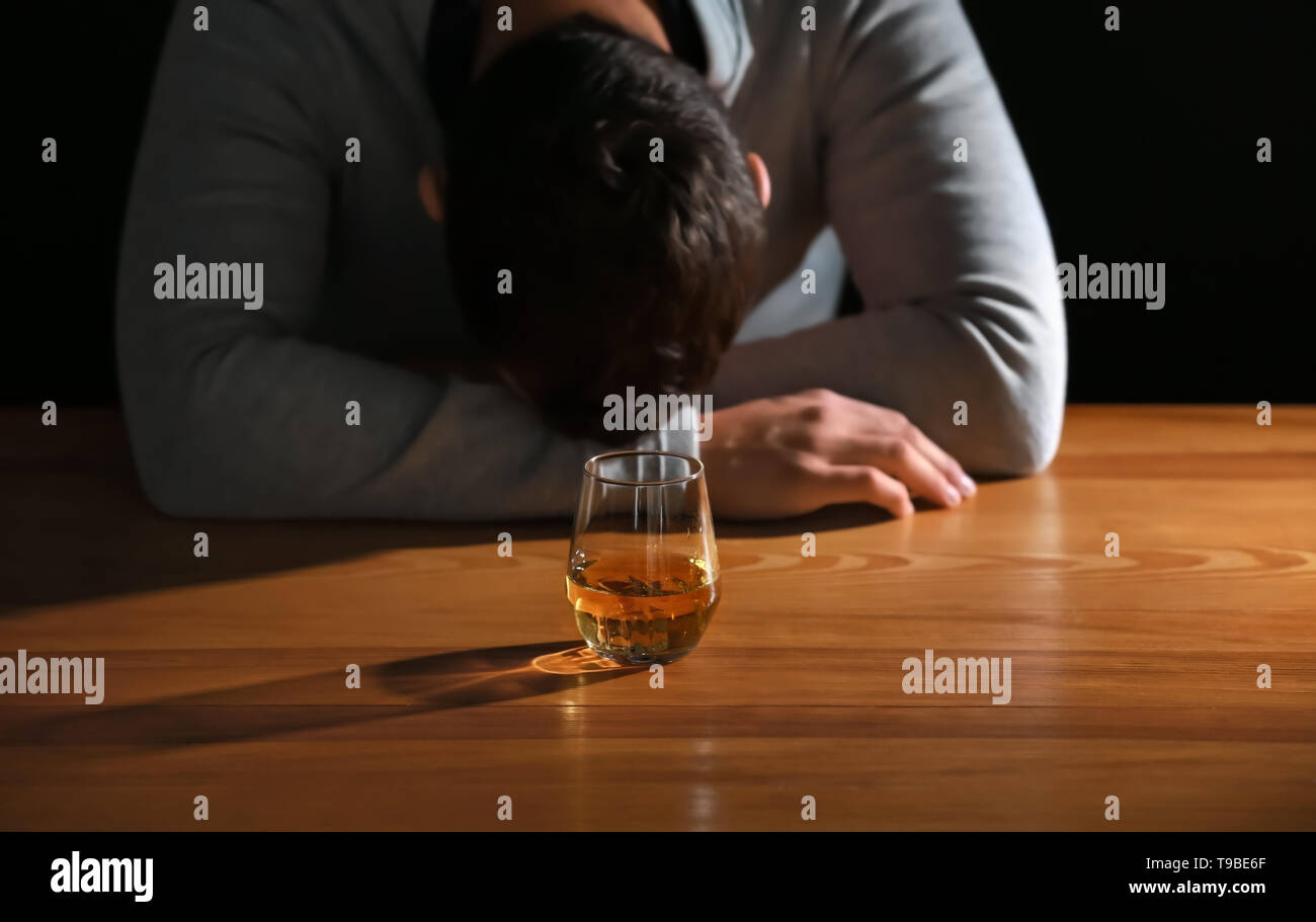 Unbewusste betrunkenen Mann mit Glas Whiskey am Tisch Stockfoto