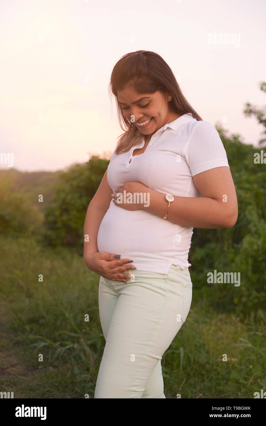 Glücklich lächelnde schwanger Hispanic Frau auf Natur Hintergrund Stockfoto