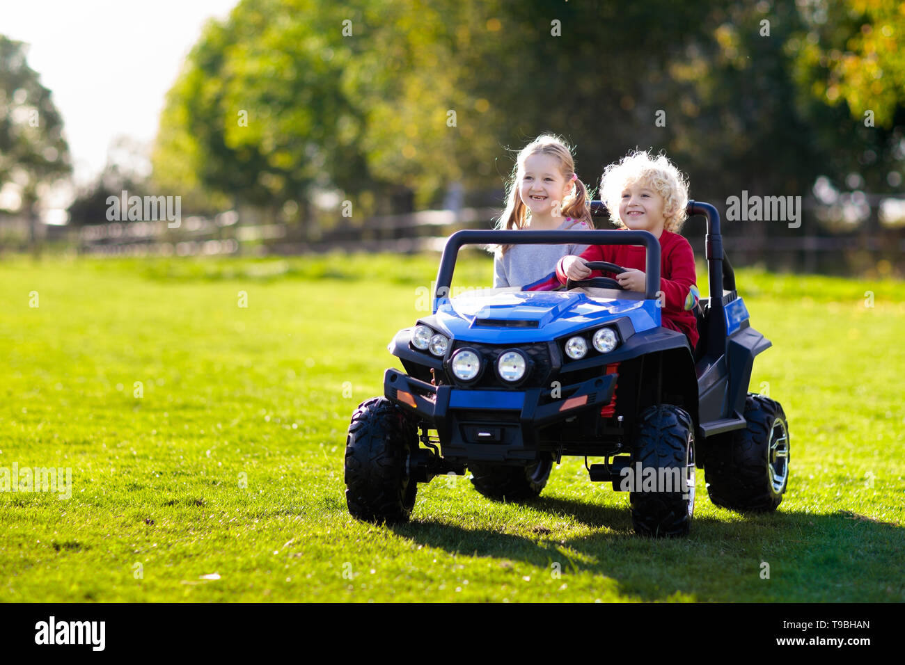 Kinder fahren elektrisch Spielzeugauto im Sommer Park. Outdoor Spielzeug.  Kinder Akku Fahrzeug. Kleine Jungen und Mädchen reiten Spielzeug-LKW im  Garten. Fam Stockfotografie - Alamy
