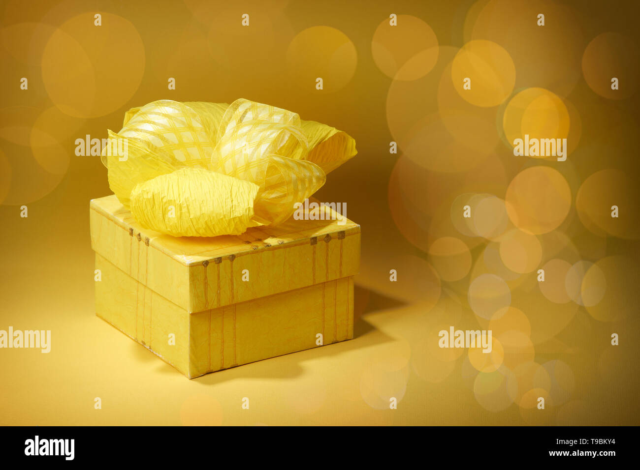 Gelber Geschenkbox mit gelben Band auf unscharfen Hintergrund Stockfoto