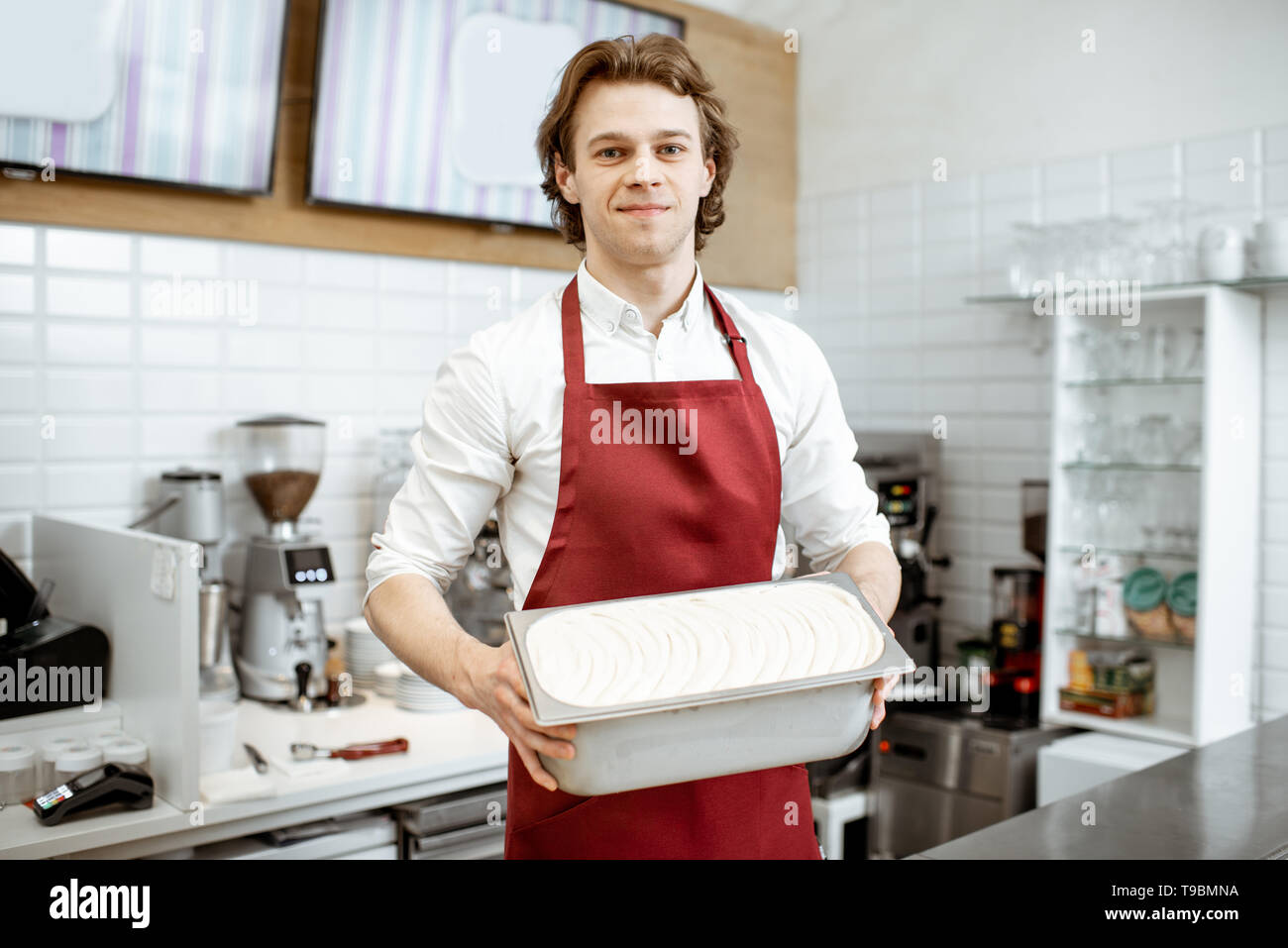 Porträt einer stattlichen Verkäufer oder Konditor in rot Schürze holding Fach mit Eis im Shop Stockfoto