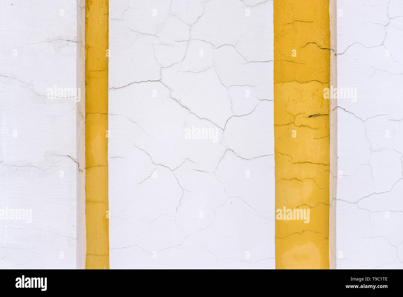 Die Wand eines alten Gebäudes. Gelbe und weiße Linien. Riss in der Wand. Risse Cement Oberfläche. Design und Architektur Stockfoto